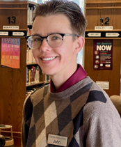 Headshot of librarian John in front of bookshelves
